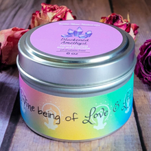 Load image into Gallery viewer, Candle tin with colorful label and purple lid on a wooden surface with flowers.