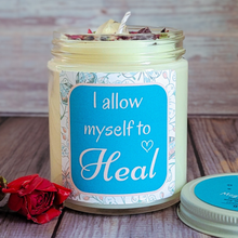 Load image into Gallery viewer, Candle jar with motivational label 'I allow myself to heal' on a wooden surface with a rose.