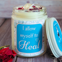 Load image into Gallery viewer, Candle in a jar with a motivational label on a wooden surface, surrounded by flowers.