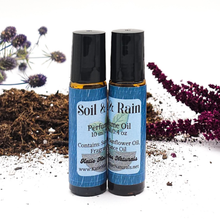 Load image into Gallery viewer, Two Soil & Rain perfume oil bottles with natural elements in the background