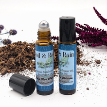 Load image into Gallery viewer, Two perfume oil bottles labeled 'Soil & Rain' with natural elements in the background.