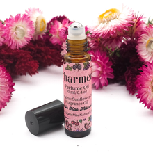 Load image into Gallery viewer, Perfume oil bottle with pink label surrounded by flowers