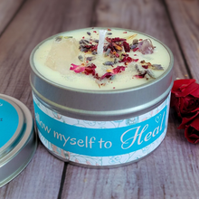 Load image into Gallery viewer, Candle in a tin labeled 'Allow myself to Heal' on a wooden surface with red flowers.

