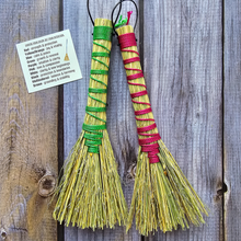 Load image into Gallery viewer, Two small brooms with pink and green handles on a wooden background
