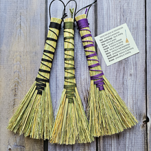 Load image into Gallery viewer, Three decorative brooms with colorful handles on a wooden surface, accompanied by a label.
